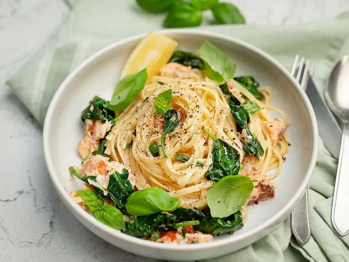 Krämig pasta med lax och spenat, toppad med färsk basilika och en citronklyfta. Smaken påminner om en mild citrusfrukt ugli.