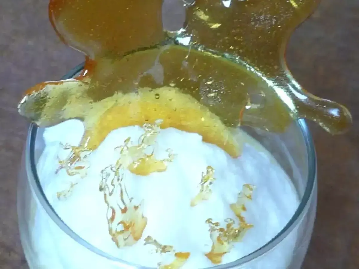 Un verre de crème aérienne surmonté d'une décoration en caramel craquant. Ces oeufs à la neige sont prêts à être dégustés.