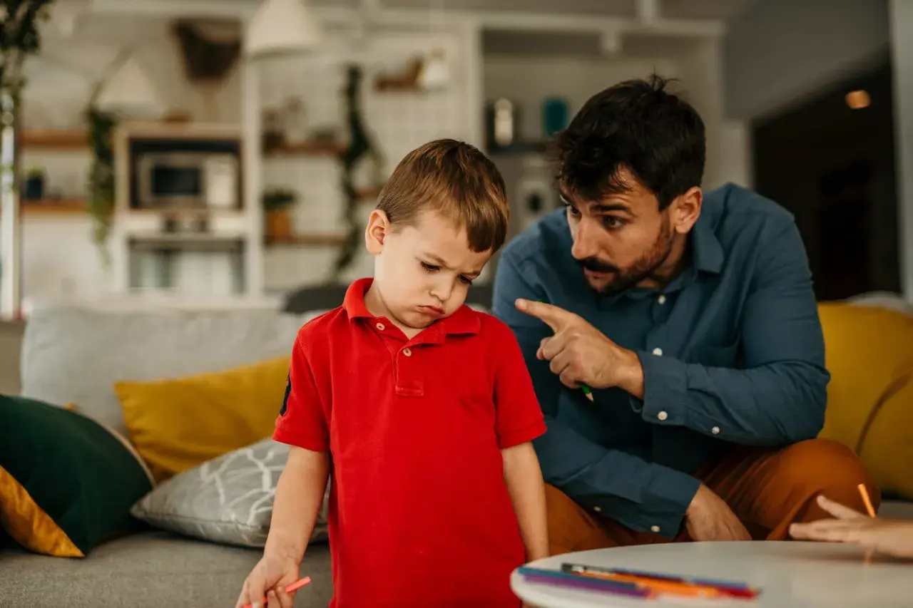 Padre explica a su hijo de 5 años cómo educar con paciencia, mientras el niño muestra una expresión de desánimo.