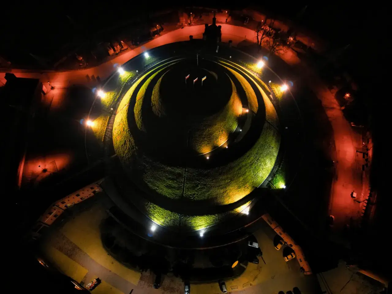 Nocne oświetlenie Kopca Kościuszki tworzy magiczną atmosferę. Kręte ścieżki i zieleń kopca lśnią w blasku reflektorów.