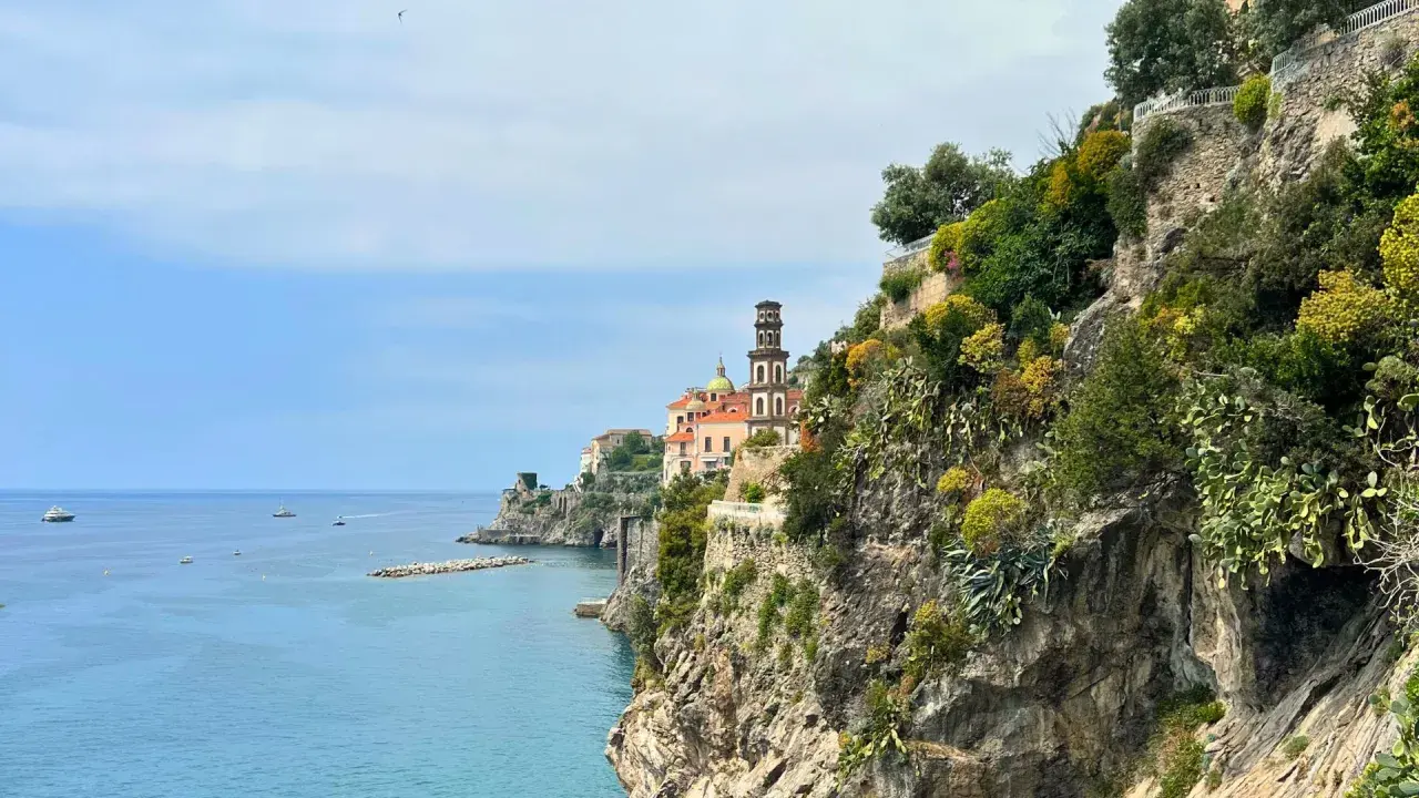 Coastal view of Amalfi with a church tower. Consider a ferry or bus for how to get from Amalfi to Naples.
