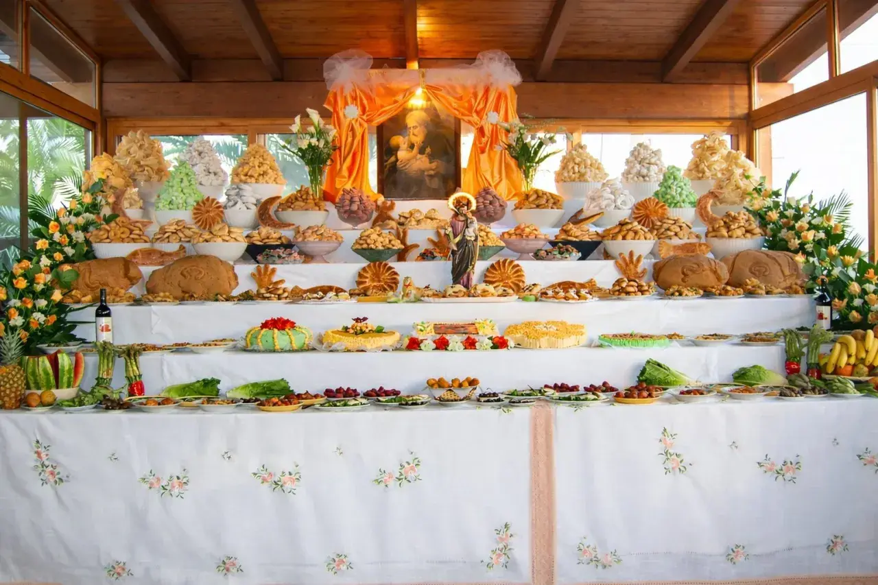 Un'abbondante tavolata ricca di dolci, pani e frutta, che celebra le tradizioni italiane con un'esposizione che ricorda un altare votivo.