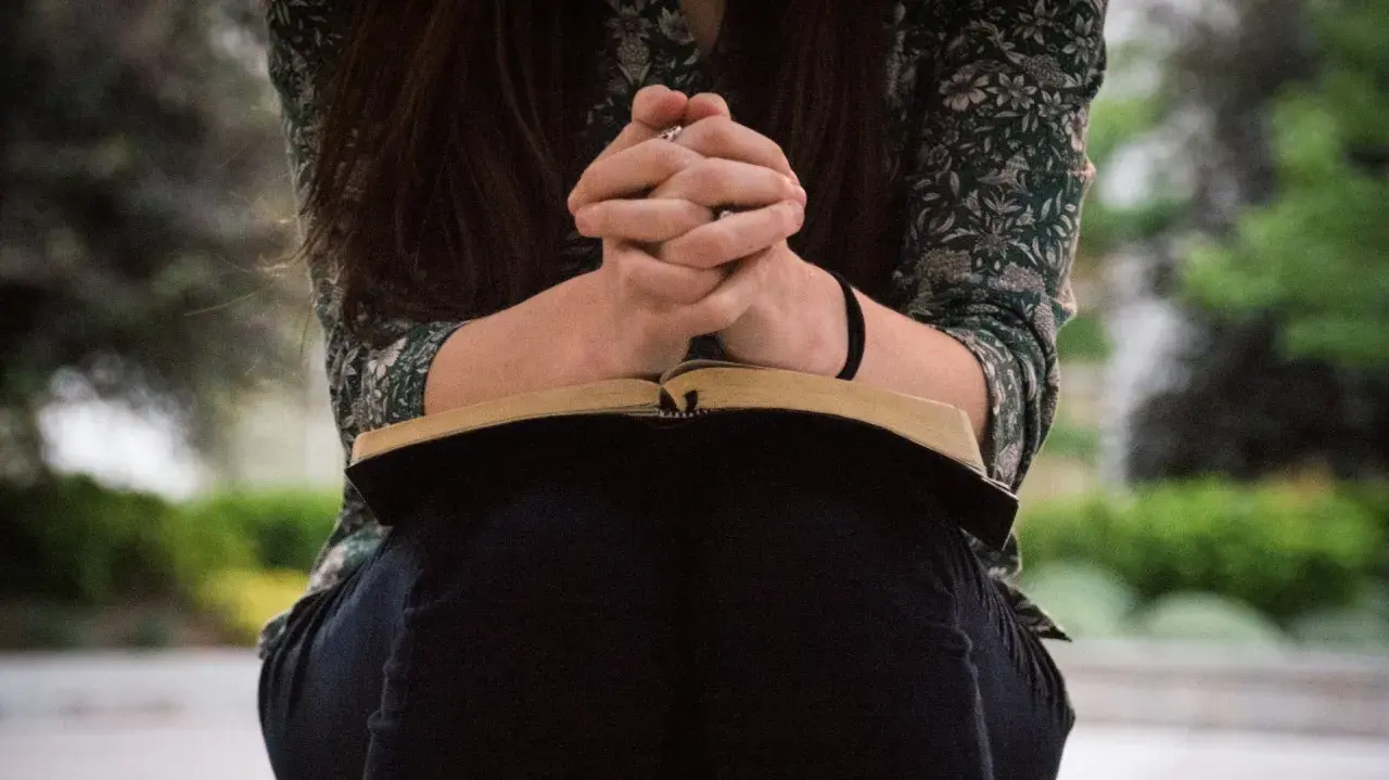 Frauenbild im Gebet mit aufgeschlagener Bibel. Ein stiller Moment der Besinnung, der das baptisten Frauenbild widerspiegelt.