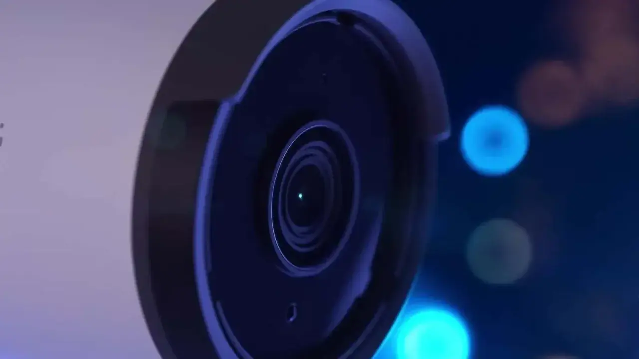 Gros plan sur l'objectif d'une caméra de surveillance, avec des lumières bleues floues en arrière-plan, évoquant le stockage vidéo surveillance.