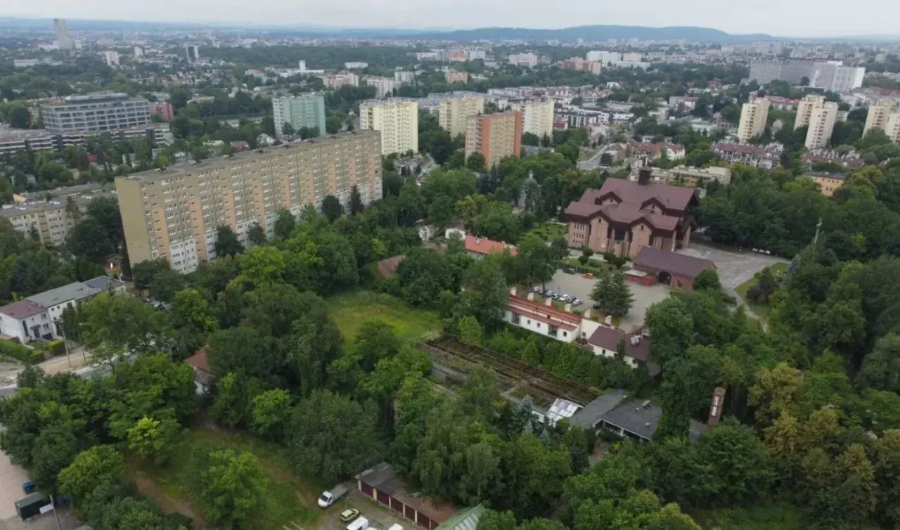 Widok na osiedle mieszkaniowe i kościół, przypominający o historii Krakowa.