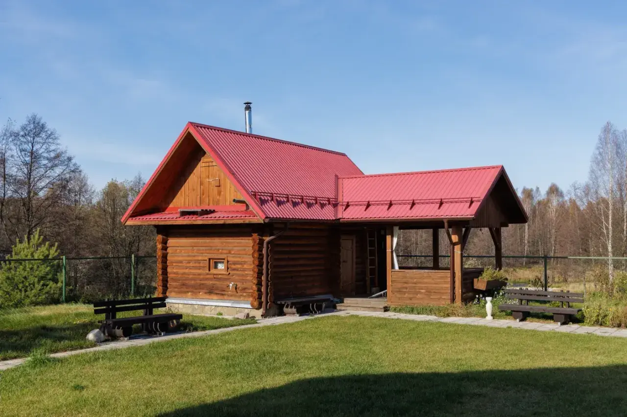 Drewniany domek z czerwoną dachem, idealny na wynajem. Możliwa dotacja na taki domek.