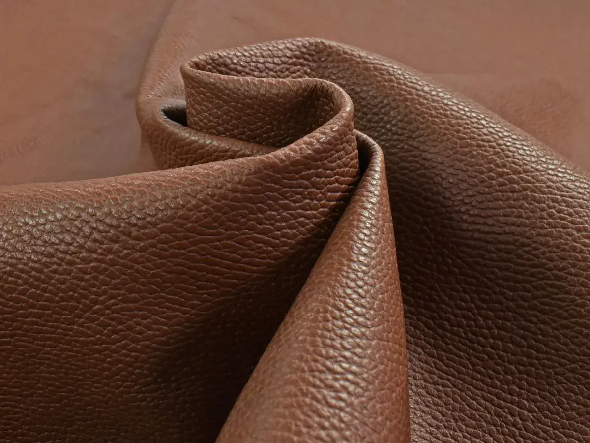 Tessuto di pelle pieno fiore marrone, con una texture granulosa che ne esalta il significato di qualità e naturalezza.