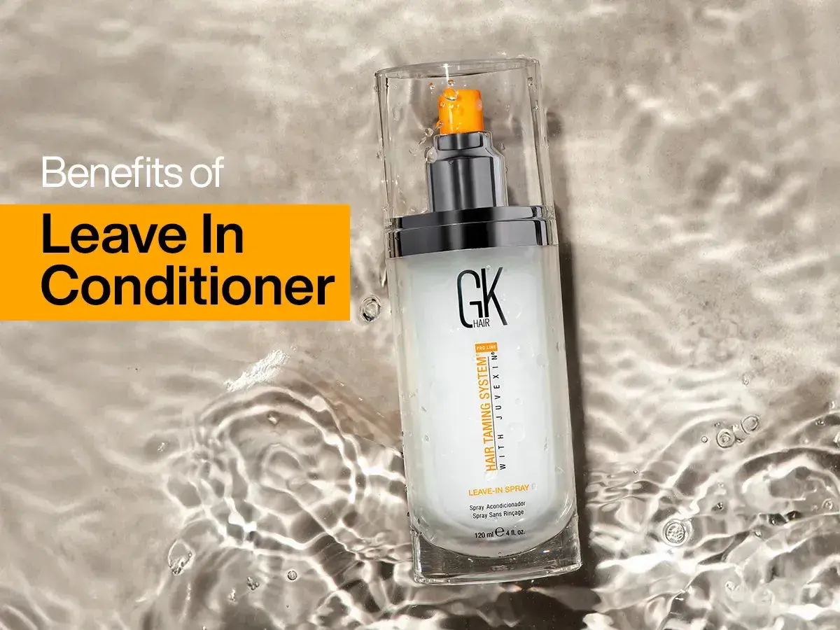 Un spray leave in para el cabello GK Hair, que promete beneficios para el pelo, descansa sobre una superficie con agua.