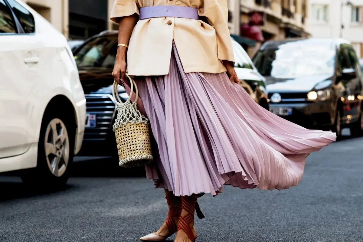 Eleganckie stylizacje z plisowaną spódnicą w pastelowym kolorze, uzupełnione wiklinową torebką i sandałami na obcasie.