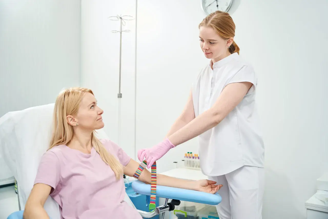 Pielęgniarka zakłada opaskę uciskową na ramię pacjentki przed pobraniem krwi na czczo.