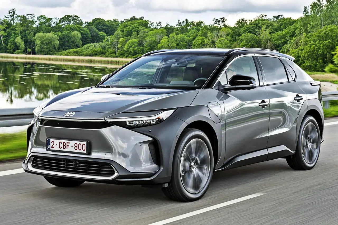 Szary Toyota bz4x cena jest atrakcyjna, gdy jedzie nad jeziorem.