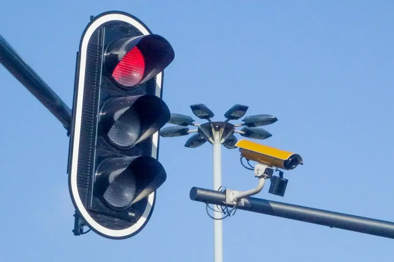 Czerwone światło na sygnalizatorze i żółta kamera monitorująca ruch. Te kamery na sygnalizacji świetlnej dbają o bezpieczeństwo.