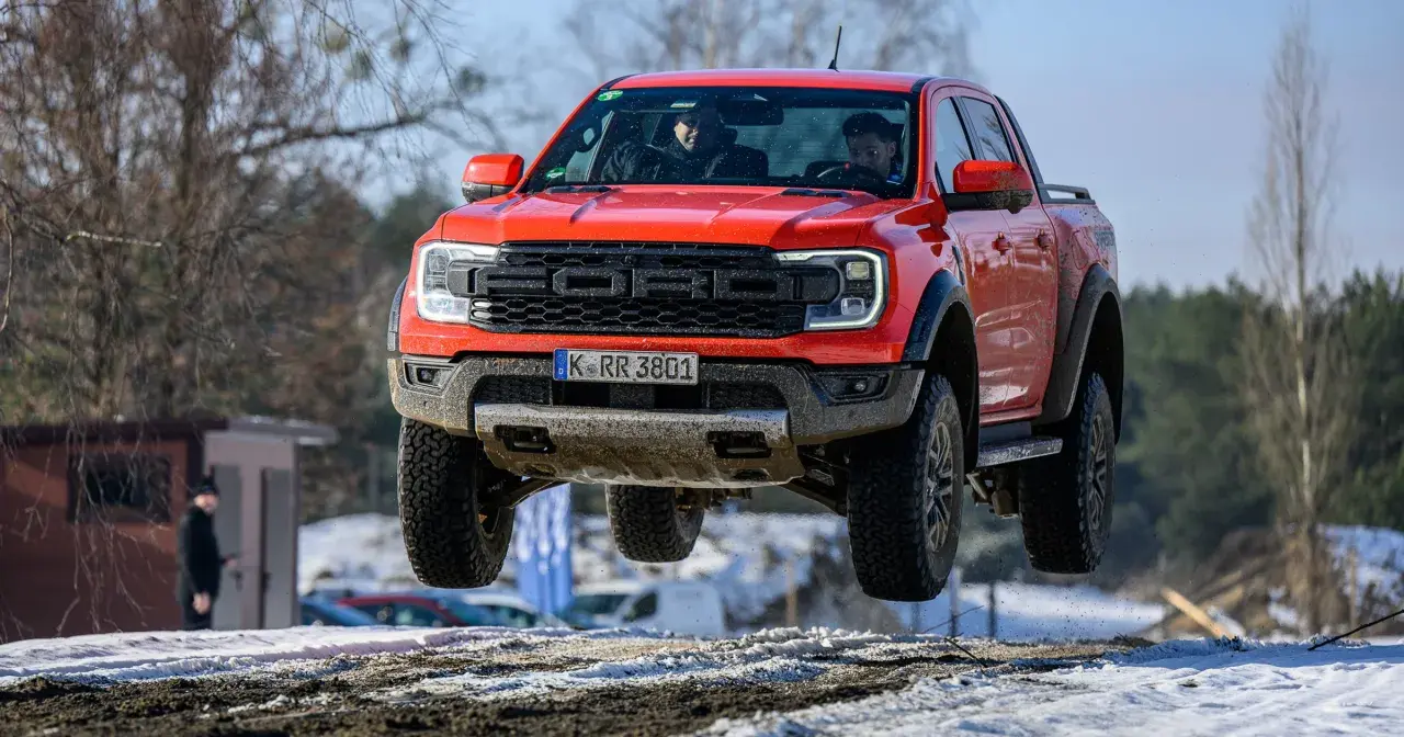 Czerwony Ford Raptor w locie nad śnieżnym terenem. Kierowcy w kabinie, a cena tego potwora budzi podziw.