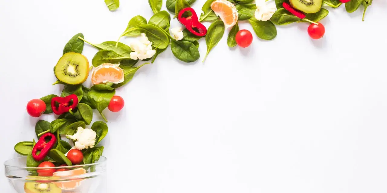 Kolorowe warzywa i owoce, takie jak kiwi, pomarańcza, papryka i pomidorki, tworzą kompozycję idealną dla diety wegańskiej.