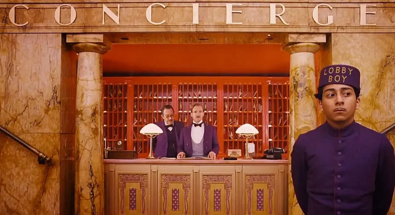 Lobby boy i dwaj recepcjoniści w hotelu, jak z filmów Wesa Andersona.