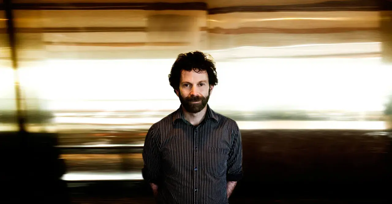Charlie Kaufman, känd för sina unika filmer, med en drömsk, suddig bakgrund som speglar hans fantasifulla berättelser.