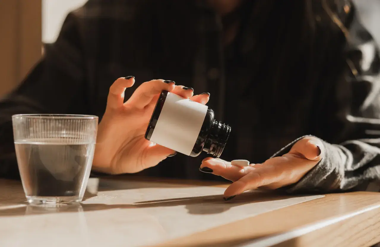 Une personne prend un comprimé de magnésium, prêt à commencer sa cure. Un verre d'eau est à proximité.