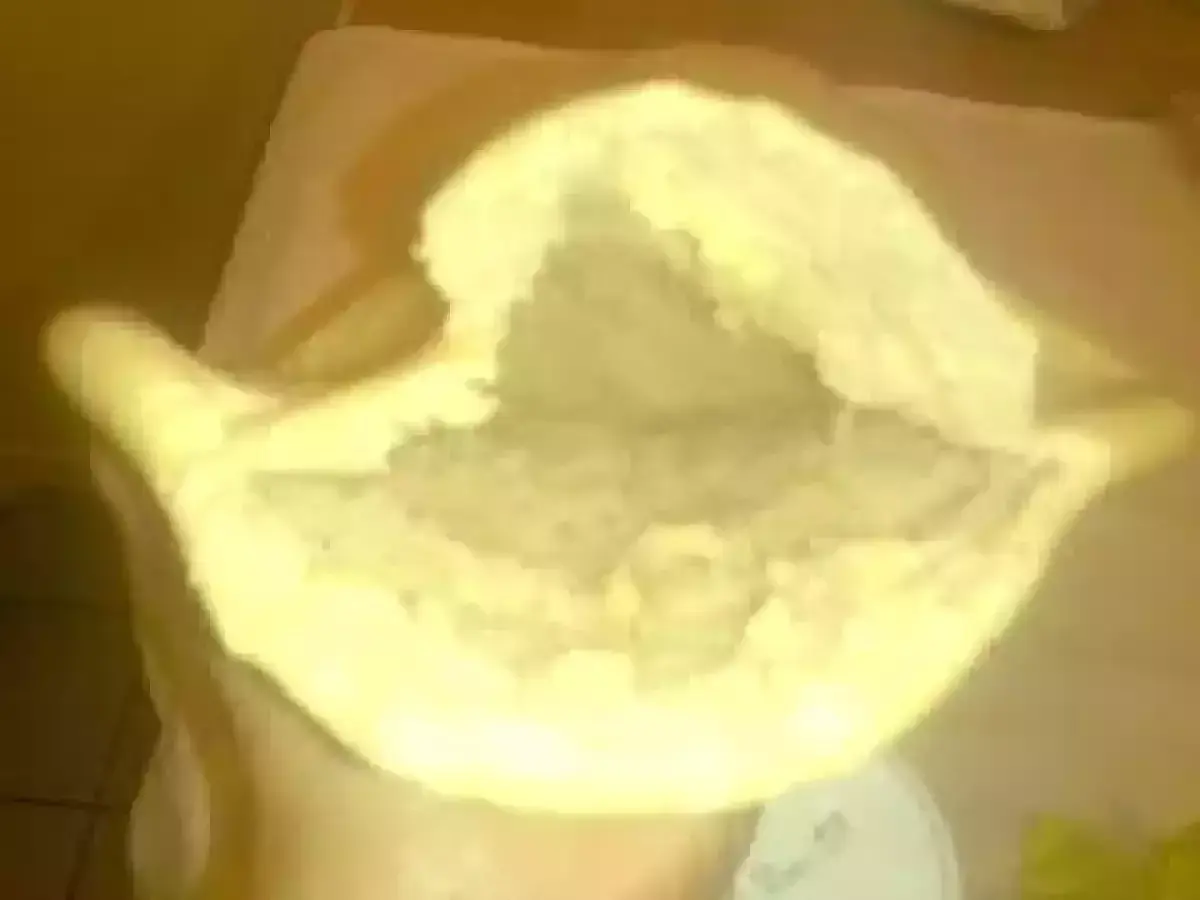Une main tient un pain libanais ouvert, prêt à être garni. Sa texture moelleuse et sa poche invitent à la gourmandise.