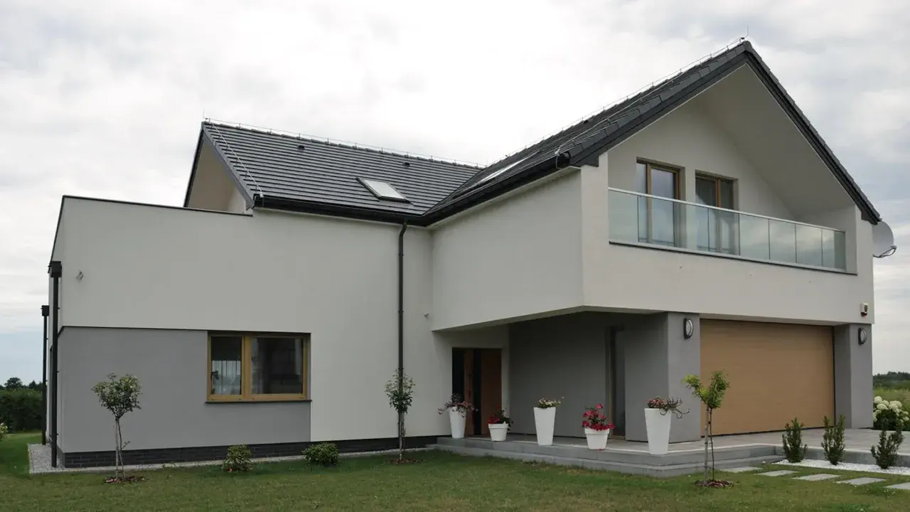 Nowoczesny dom z dwuspadowym dachem i balkonem. Ocieplenie domu wzory tynków w odcieniach bieli i szarości.
