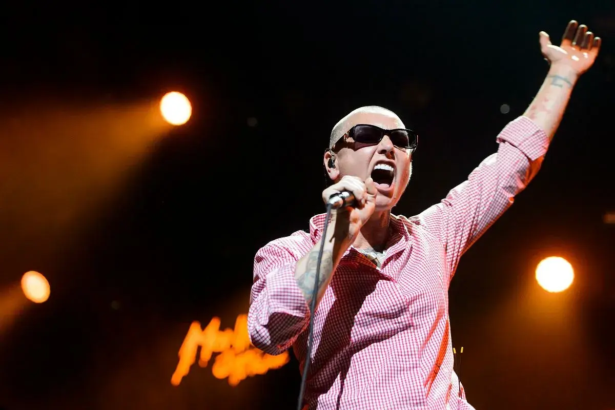 Sinéad O'Connor na koncercie, z ręką w górze, śpiewa swoje legendarne utwory.