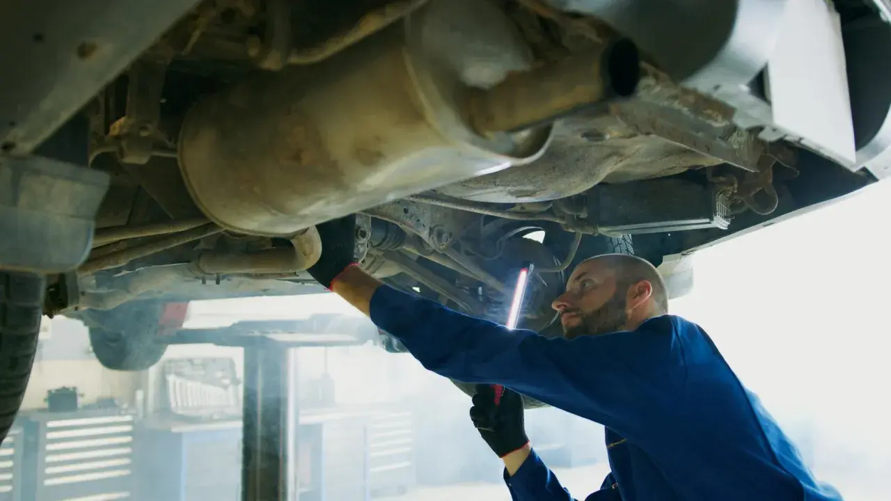 Mechanik bada podwozie Opla, szukając przyczyny błędu DTC P0420.