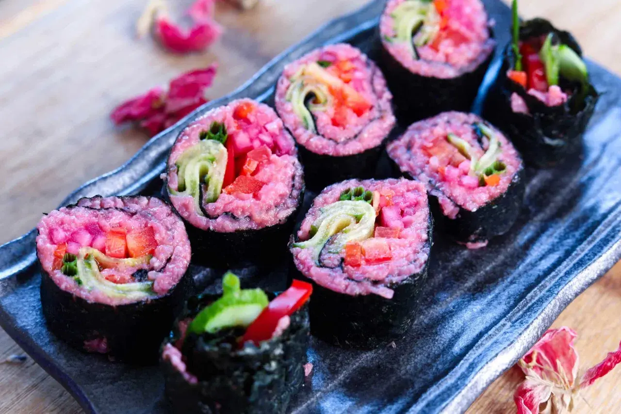 Sushi rolls with vibrant pink rice, filled with fresh vegetables like cucumber and red pepper. A delightful pink rice recipe for a colorful meal.