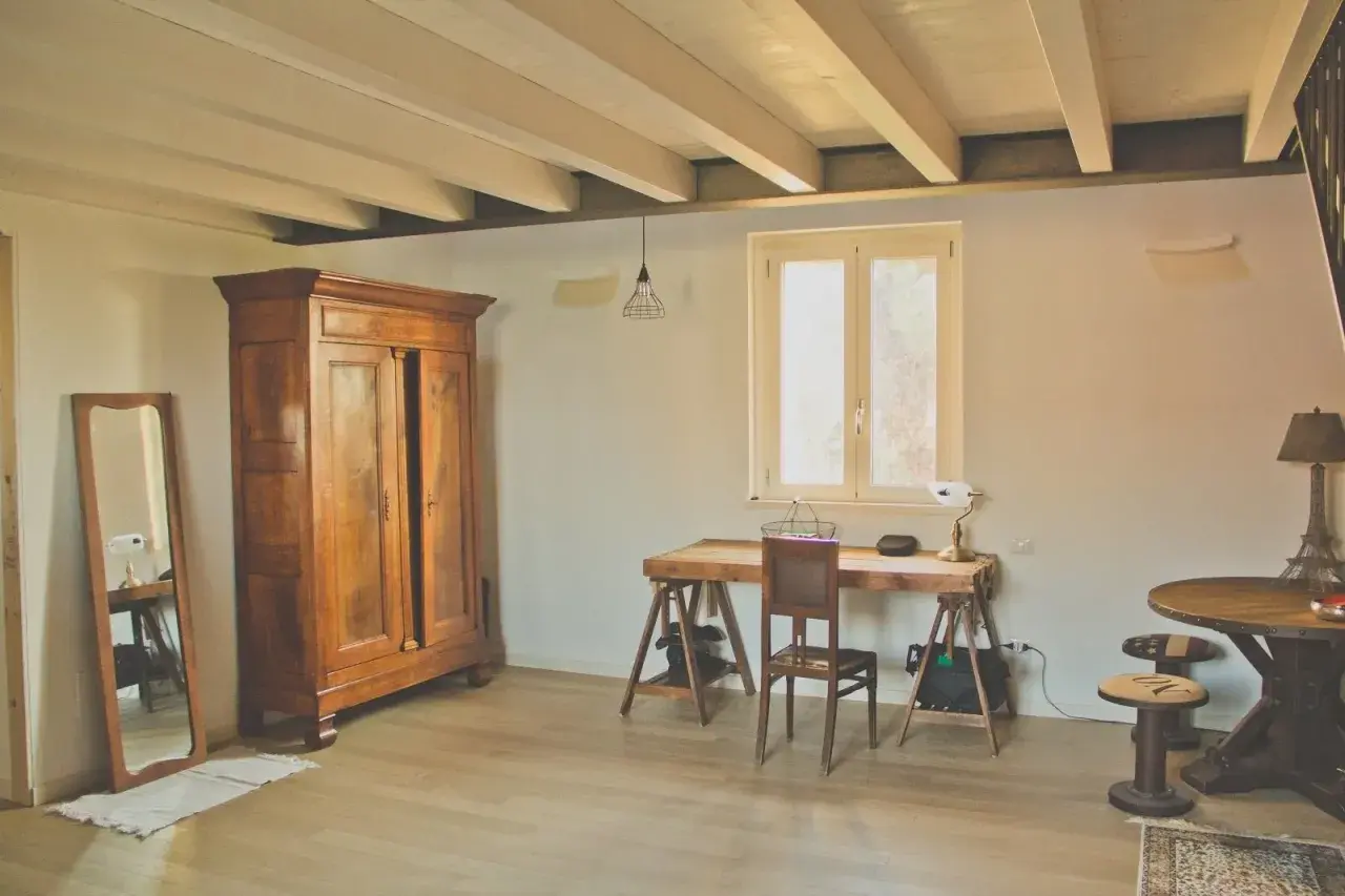Arredare casa in campagna fai da te: armadio antico, scrivania rustica, specchio e lampada con base Torre Eiffel.
