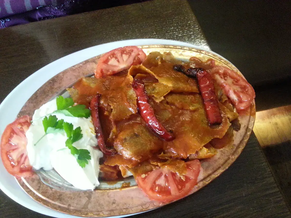 Iskender kebab z sosem pomidorowym, jogurtem, papryczkami i pomidorami.