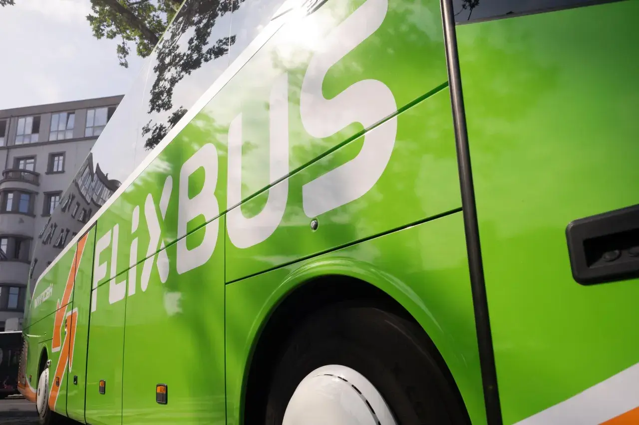 Zielony autobus FlixBus z białym logo, widok z boku.