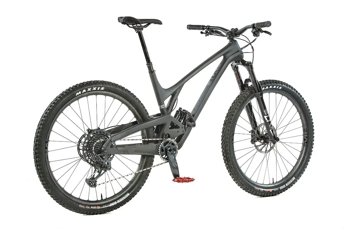 A dark grey Evil Offering mountain bike, ready for an evil offering review. Features Maxxis tires and red pedals.