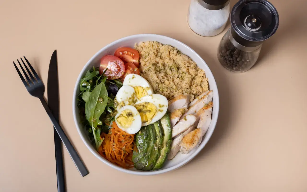 Une salade composée excellente avec poulet grillé, œufs durs, avocat, tomates cerises, carottes râpées et quinoa.