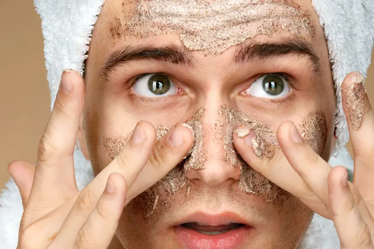 Uomo con scrub viso, pronto per la cura della pelle. Cosa mettere dopo lo scrub viso per un risultato ottimale.