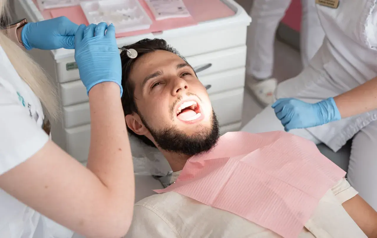 Pacjent u dentysty, który bada zęby. Może to być próchnica pod plombą, która wymaga uwagi.