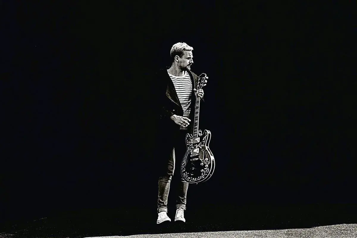 Paweł Domagała z gitarą, jakby gotowy do wykonania utworu "Weź nie pytaj".
