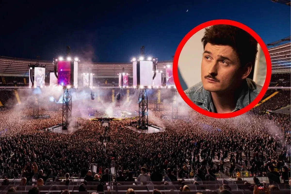 Gwiazda z wąsem na tle tłumu na największym koncercie w Polsce. Stadion wypełniony po brzegi, światła i dym tworzą niesamowitą atmosferę.