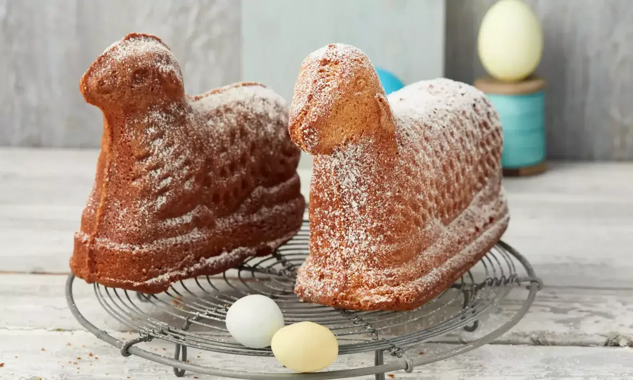 Zwei goldbraune Osterlämmer, mit Puderzucker bestäubt, auf einem Gitter. Ein perfektes Osterlamm Rezept für das Fest.