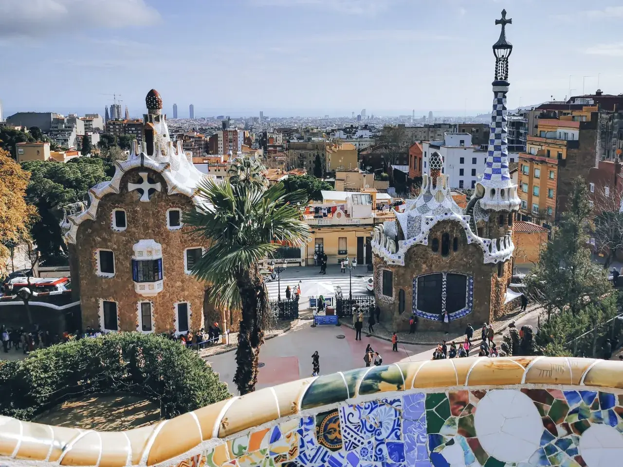 Bunte Mosaike und märchenhafte Gebäude im Park Güell, ein Wahrzeichen von Barcelona. Die Skyline der Stadt im Hintergrund.