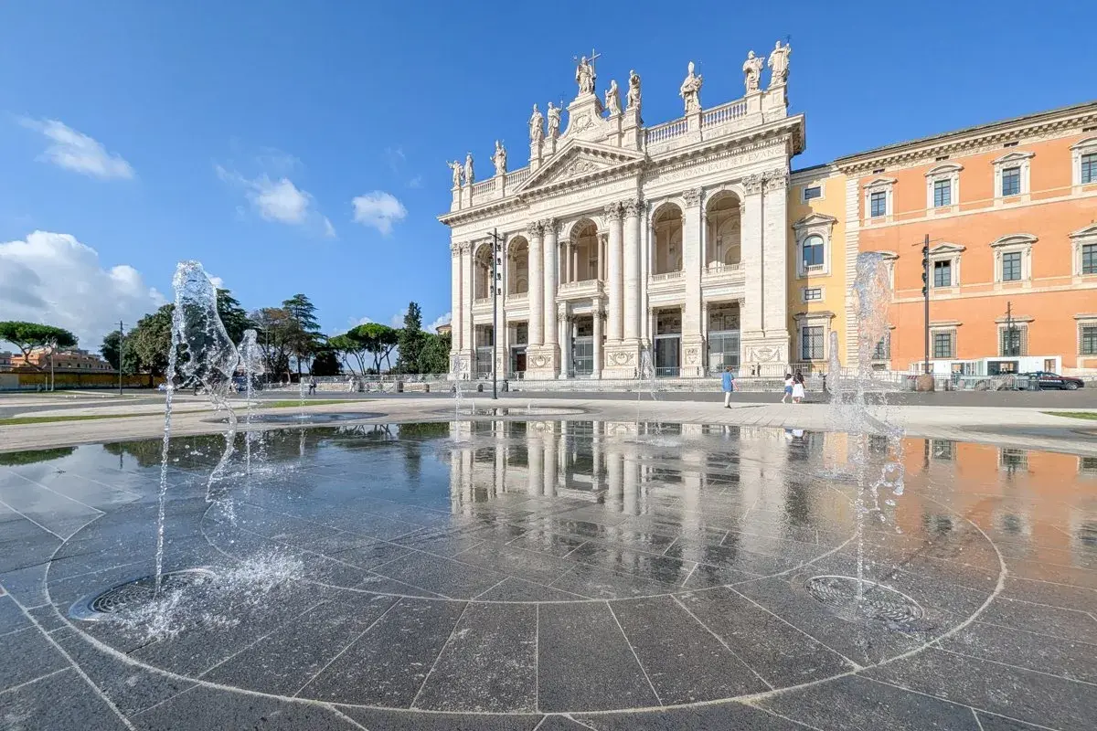 La fontaine devant la cathédrale de Rome, Saint-Jean-de-Latran, reflète le ciel bleu et l'architecture imposante.