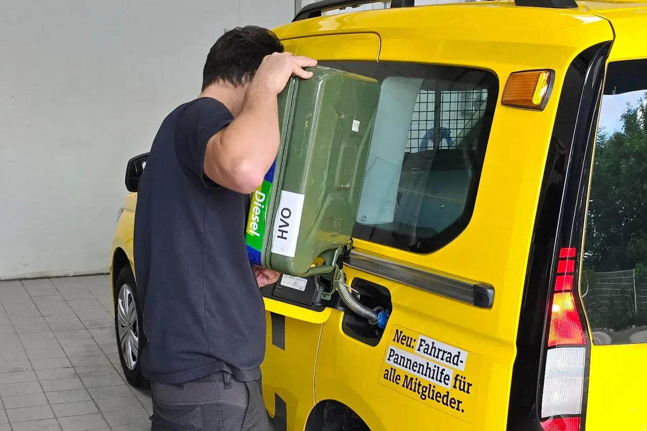 Uomo versa diesel paraffinico da tanica verde in un furgone giallo.
