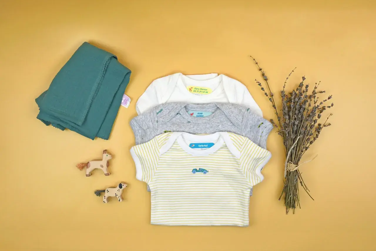 Trois bodies pour bébé avec des étiquettes personnalisées. Apprenez comment enlever une étiquette thermocollante pour réutiliser ces vêtements.