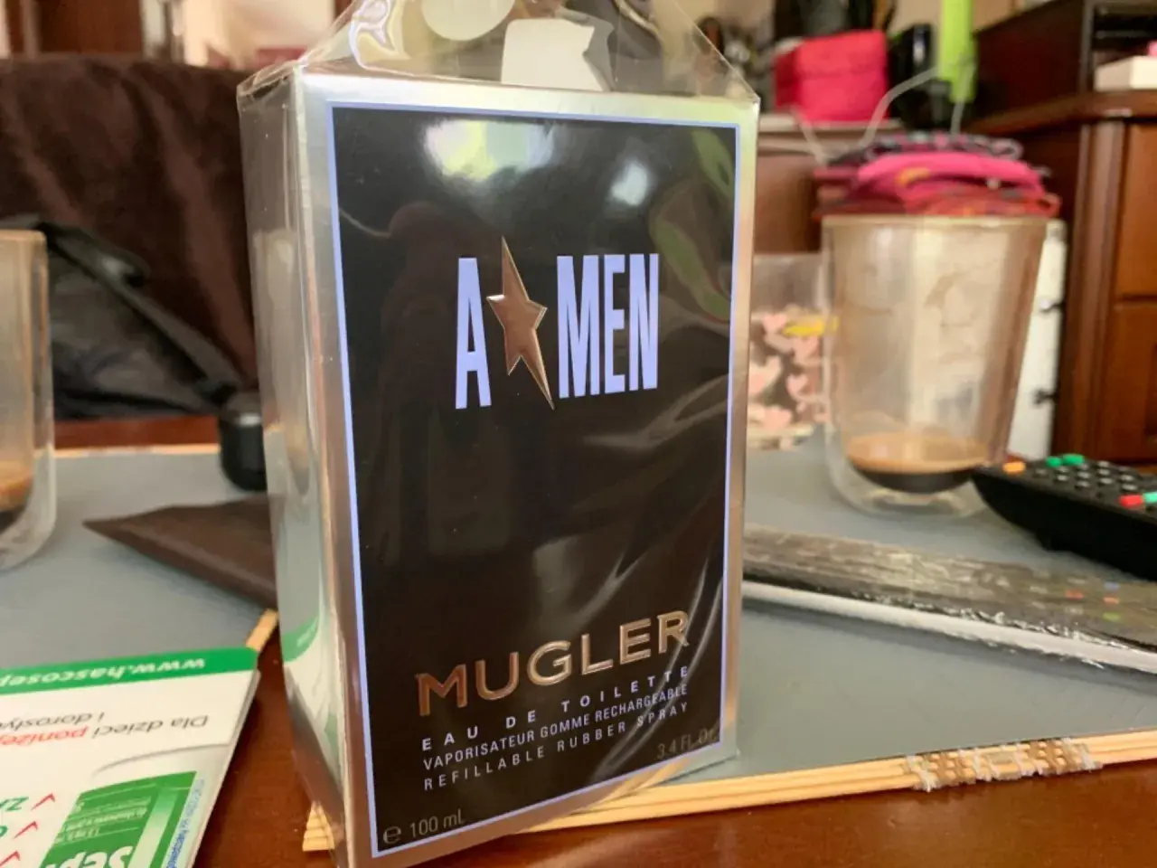 Pudełko perfum Mugler A*Men, zapach dla mężczyzny, w folii, na stole obok szklanki.