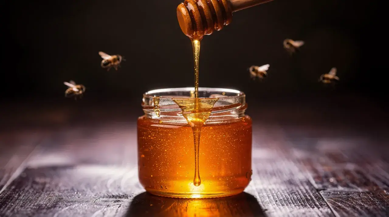 Un tarro de miel dorada, con abejas revoloteando, parece un sueño con miel.