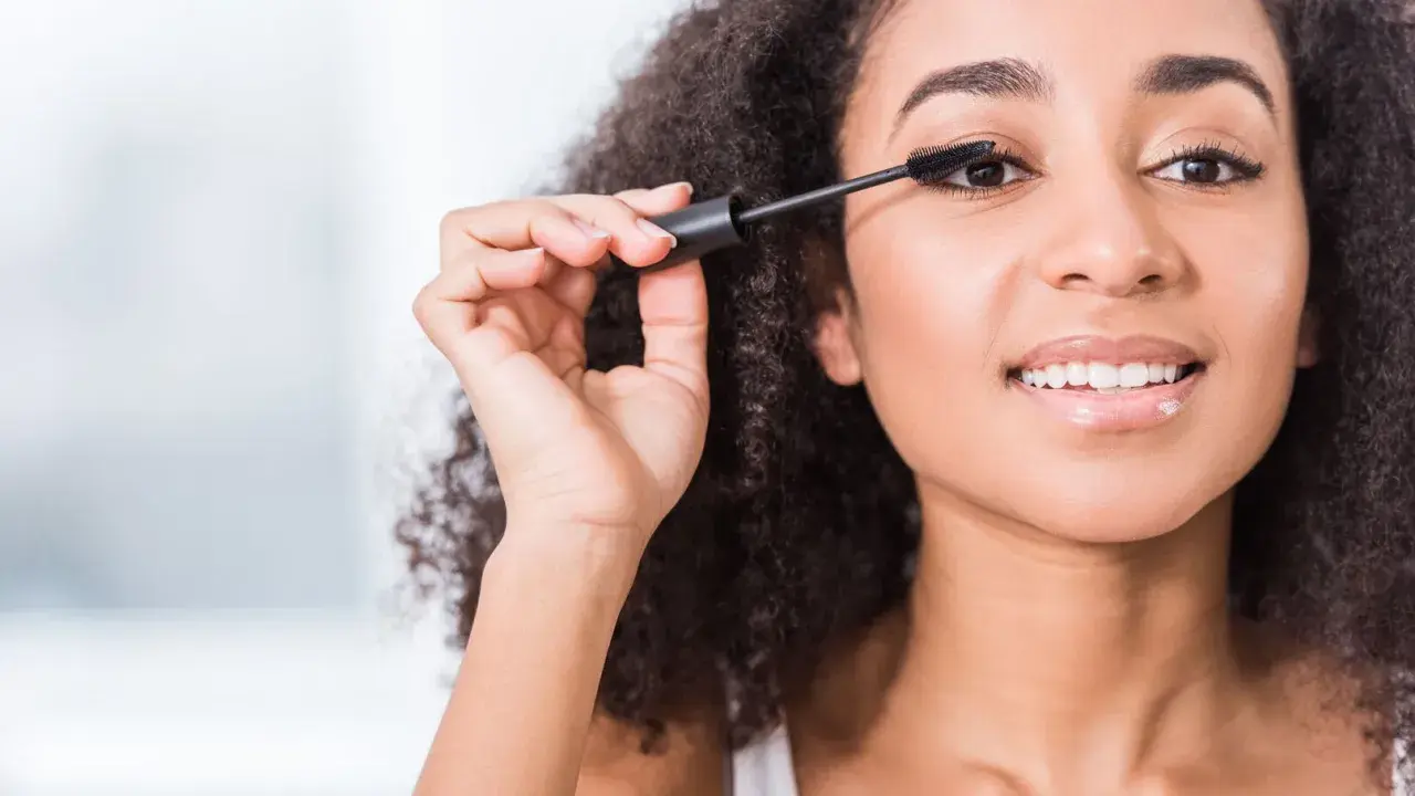Une femme applique du mascara, ses cils s'allongent. Elle sourit, le mascara qui coule est évité.