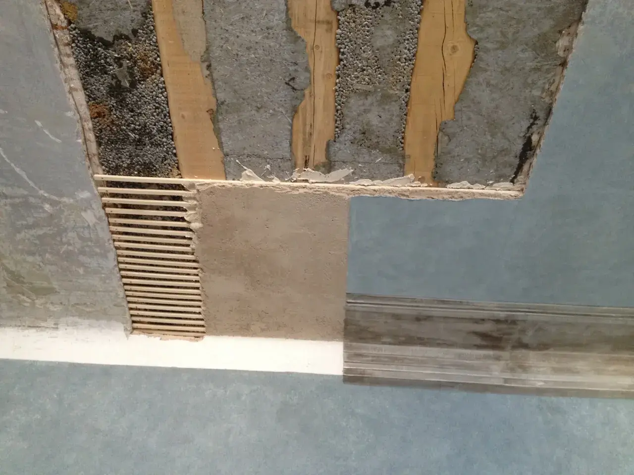 Soffitto in fase di ristrutturazione, con travi a vista e intonaco parzialmente rimosso. Si vede come rasare un soffitto rovinato, con listelli di legno e nuovo intonaco.
