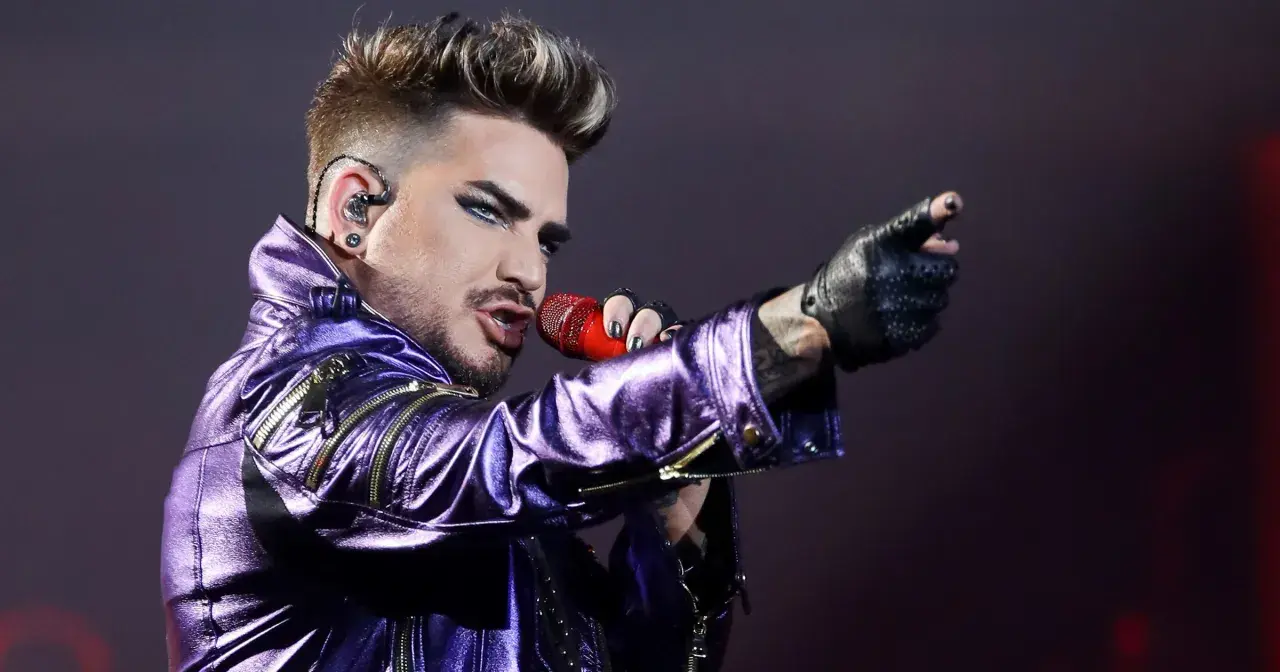 Adam Lambert w błyszczącej, fioletowej kurtce śpiewa z mikrofonem, wskazując palcem. To jakby Queen powrócił na scenę z nową energią.