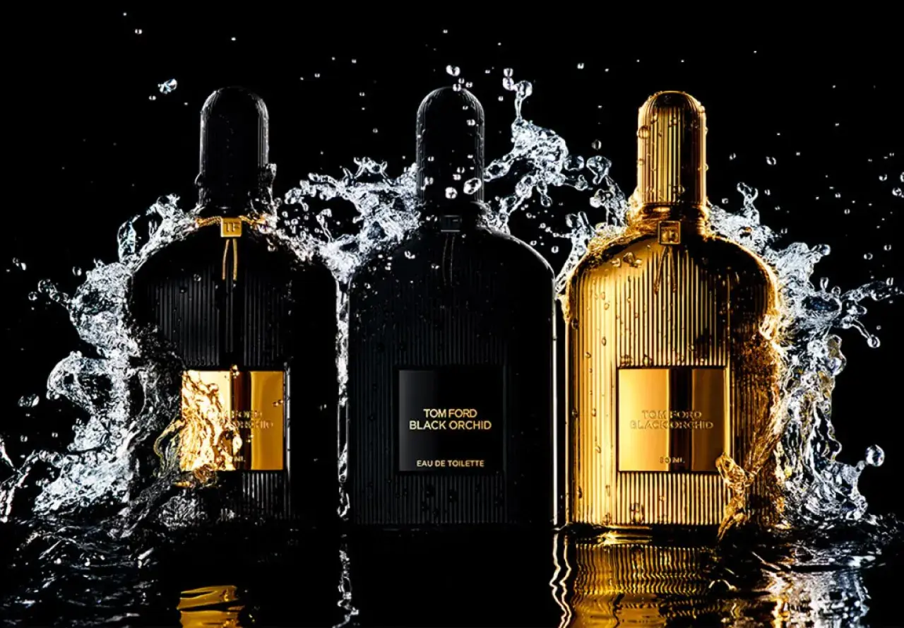 Trzy flakony perfum Tom Ford Black Orchid, w tym jeden złoty, otoczone wodnymi rozpryskami. Wyczuwalna nuta wanilii.