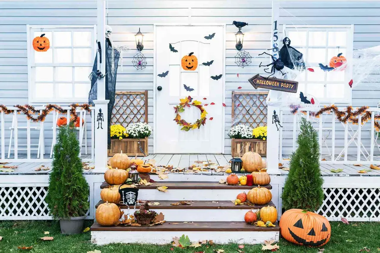 Porche decorado para Halloween con calabazas, telarañas, murciélagos y un esqueleto.
