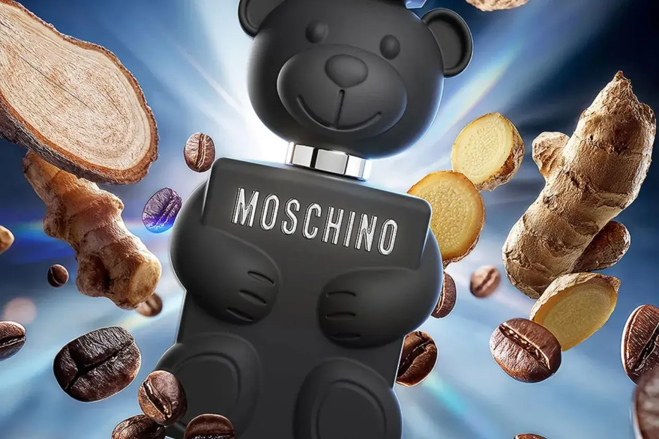 Czarny flakon Moschino Toy Boy w kształcie misia otoczony ziarnami kawy i imbirem.