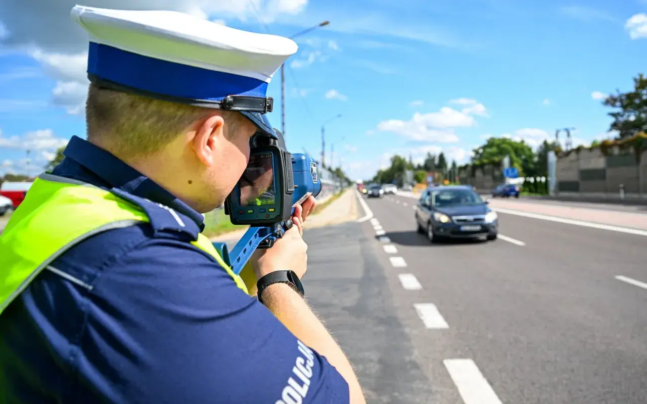 Policjant mierzy prędkość pojazdu, aby ustalić taryfikator punktów karnych.
