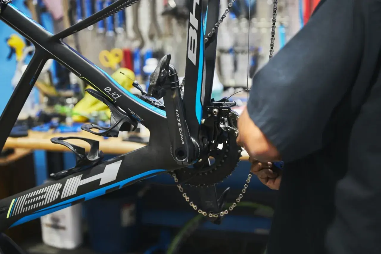 Mechanik dokonuje regulacji przedniej przerzutki w rowerze szosowym. Widać korbę Ultegra i ramę BH.